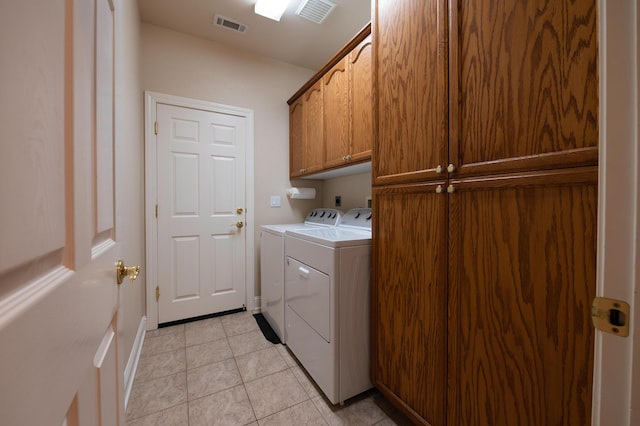 clothes washing area with washer and clothes dryer, cabinets, and light tile patterned flooring