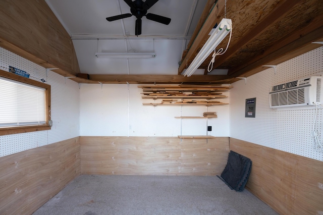 carpeted empty room featuring ceiling fan, wooden walls, a workshop area, and a wall mounted AC