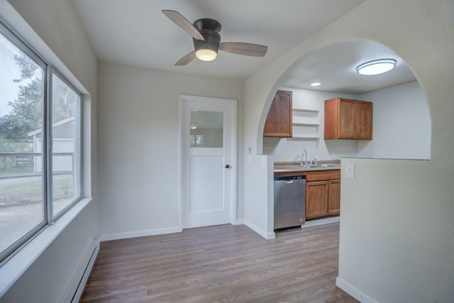 kitchen featuring stainless steel dishwasher, baseboard heating, ceiling fan, sink, and light hardwood / wood-style floors