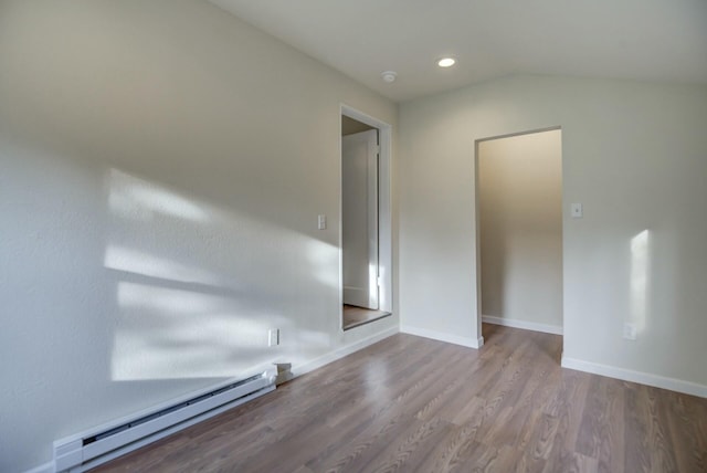 spare room featuring hardwood / wood-style floors, vaulted ceiling, and baseboard heating