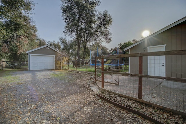 view of yard with a trampoline, a garage, and an outdoor structure