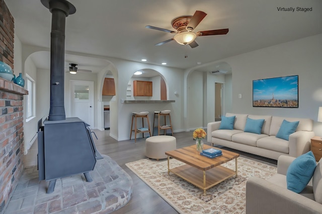 living room featuring a wood stove, ceiling fan, and hardwood / wood-style floors