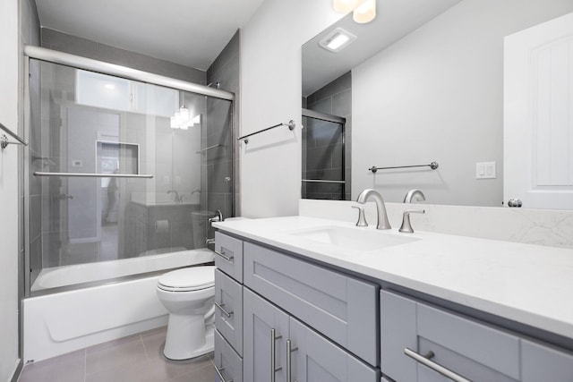 full bathroom with tile patterned floors, vanity, toilet, and bath / shower combo with glass door