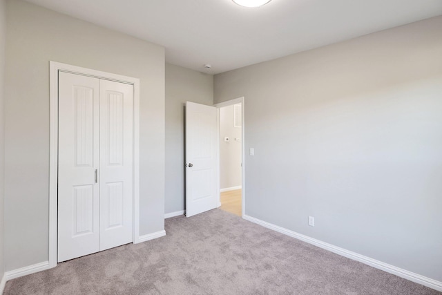 unfurnished bedroom with light colored carpet and a closet