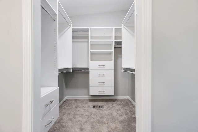 spacious closet with light colored carpet and vaulted ceiling