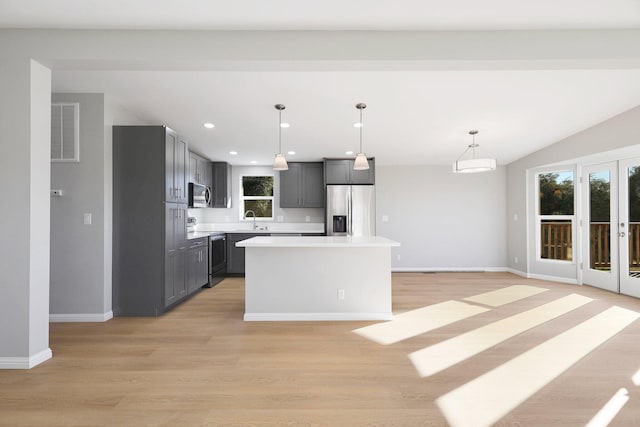 kitchen featuring appliances with stainless steel finishes, pendant lighting, light hardwood / wood-style flooring, a center island, and gray cabinets