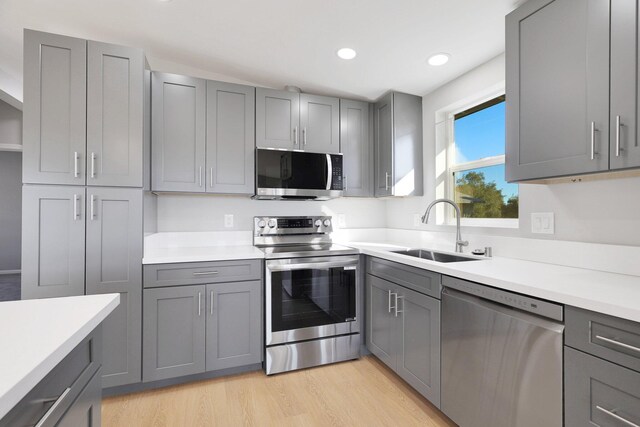 kitchen featuring gray cabinets, sink, light wood-type flooring, and stainless steel appliances