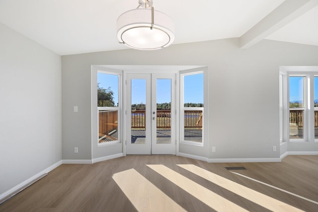 unfurnished dining area featuring lofted ceiling with beams, french doors, and wood-type flooring