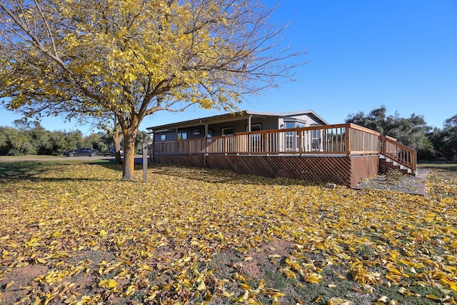 rear view of property featuring a lawn and a deck