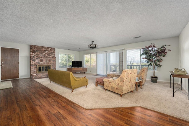 living room with hardwood / wood-style flooring, a fireplace, and a textured ceiling