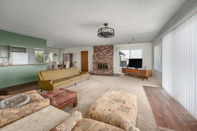 living room with light wood-type flooring, a textured ceiling, and a brick fireplace