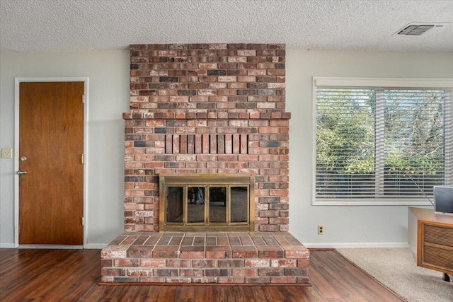 unfurnished living room with a fireplace, dark hardwood / wood-style flooring, and a textured ceiling