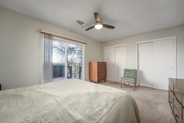 carpeted bedroom featuring ceiling fan, a textured ceiling, access to outside, and multiple closets