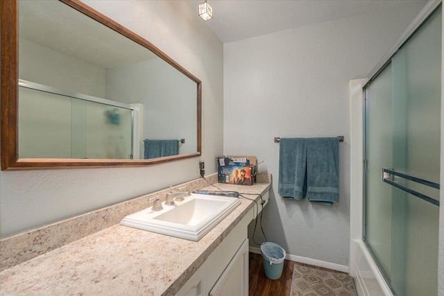 bathroom with combined bath / shower with glass door, vanity, and hardwood / wood-style flooring