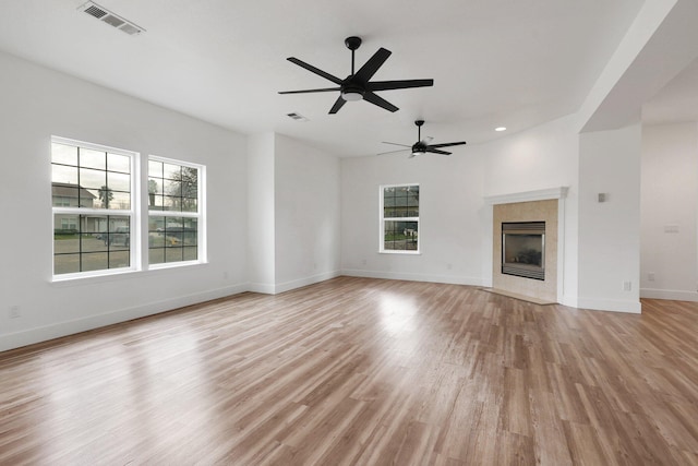 unfurnished living room with a tile fireplace, light wood-type flooring, and ceiling fan