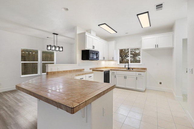 kitchen with kitchen peninsula, a breakfast bar, sink, decorative light fixtures, and white cabinets