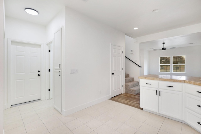 kitchen featuring tile countertops, ceiling fan, white cabinetry, and light tile patterned floors