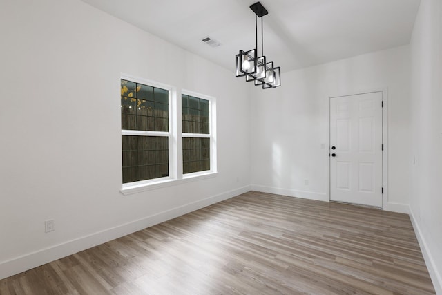 empty room featuring a chandelier and hardwood / wood-style flooring