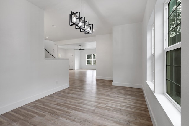 interior space featuring ceiling fan with notable chandelier and light wood-type flooring