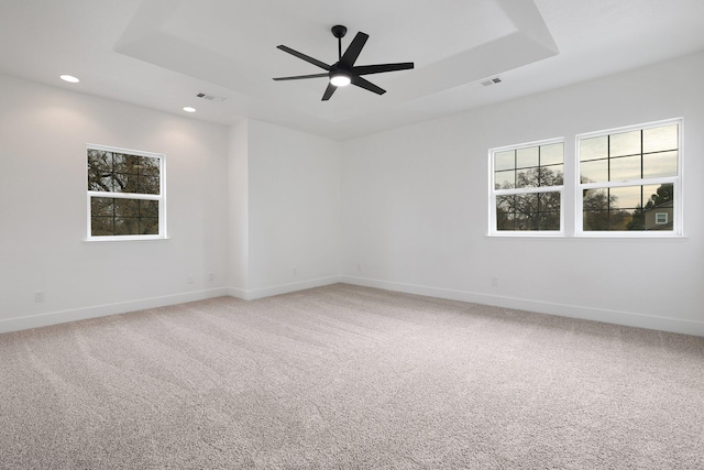 carpeted empty room with a tray ceiling and ceiling fan