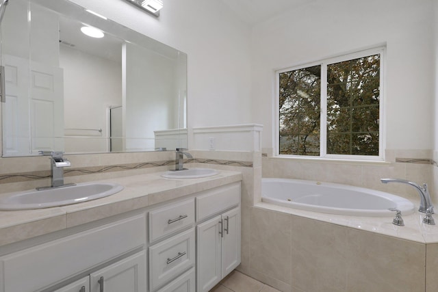 bathroom featuring tile patterned floors, vanity, and tiled bath