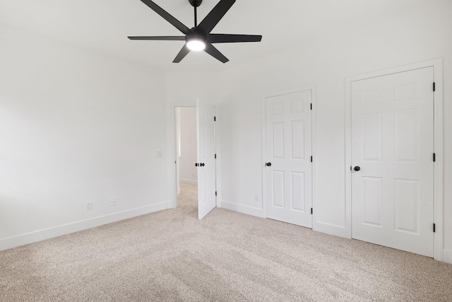 unfurnished bedroom with light carpet, two closets, and ceiling fan