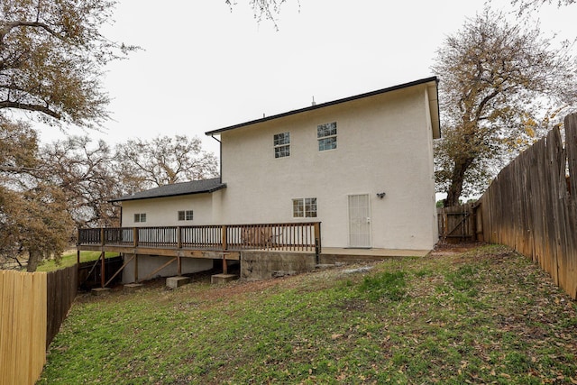 back of property featuring a lawn and a deck