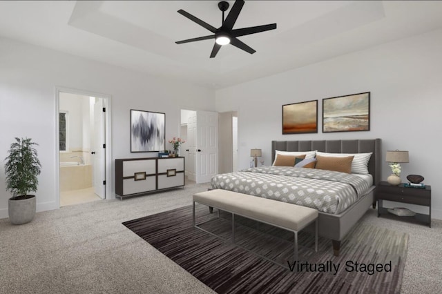 carpeted bedroom with a raised ceiling, ensuite bathroom, and ceiling fan