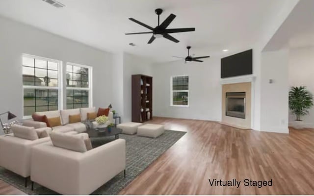 living room with hardwood / wood-style flooring, ceiling fan, and a fireplace