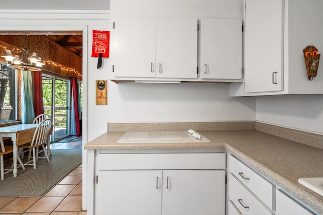 kitchen featuring white cabinets, light tile patterned floors, white electric cooktop, and a chandelier