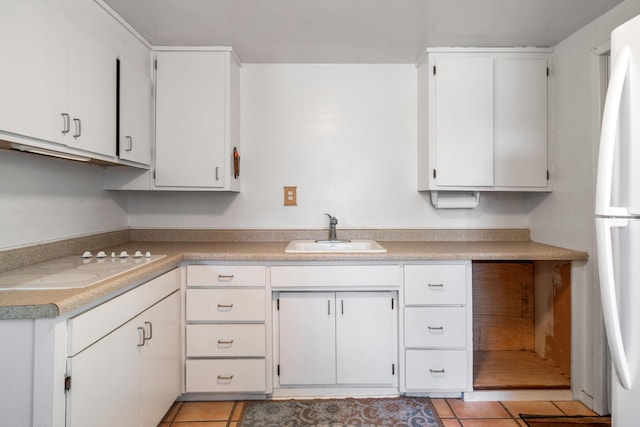 kitchen featuring light tile patterned flooring, refrigerator, white cabinetry, and sink