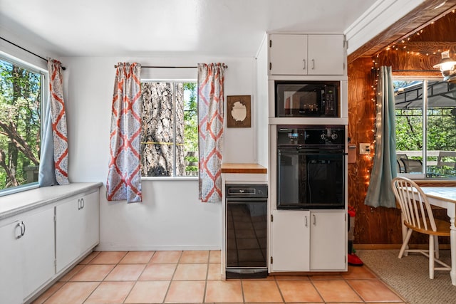 kitchen with white cabinets, light tile patterned floors, plenty of natural light, and black appliances