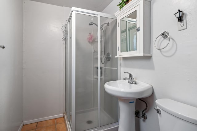 bathroom featuring toilet, tile patterned floors, a shower with door, and sink