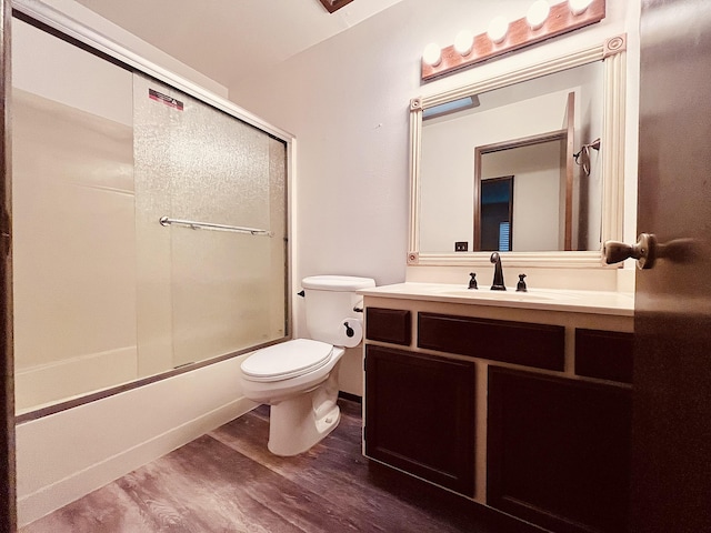 full bathroom with shower / bath combination with glass door, hardwood / wood-style floors, vanity, and toilet