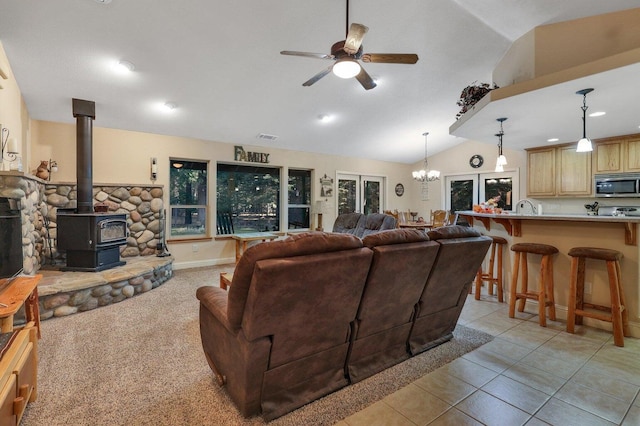 tiled living room with a wood stove, ceiling fan with notable chandelier, and lofted ceiling