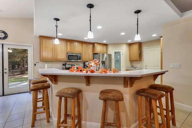 kitchen featuring a breakfast bar, hanging light fixtures, light tile patterned floors, and stainless steel appliances