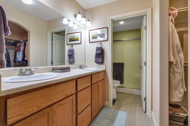 bathroom featuring tile patterned floors, vanity, toilet, and walk in shower