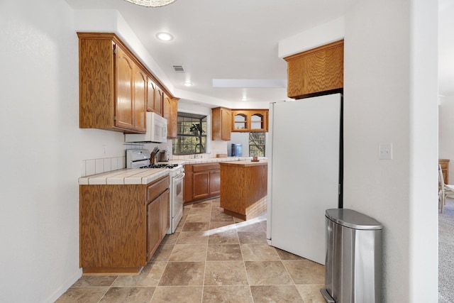 kitchen with tile countertops, a kitchen island, and white appliances