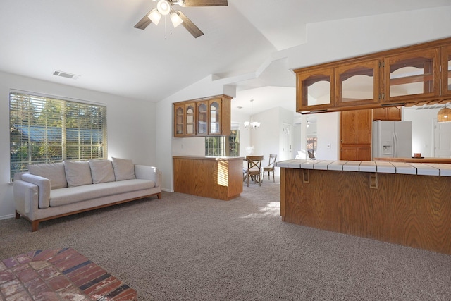 unfurnished living room with ceiling fan with notable chandelier, light colored carpet, and vaulted ceiling