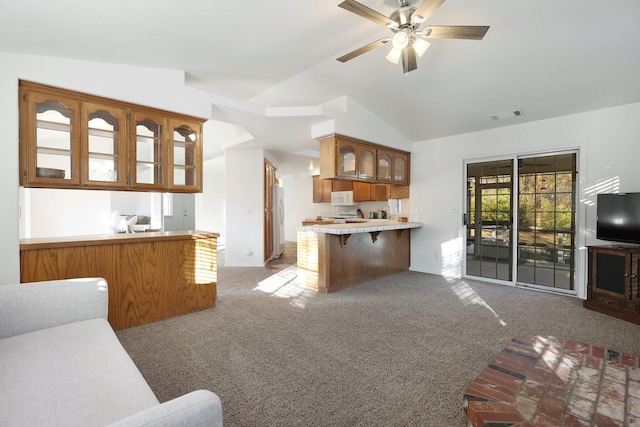 kitchen with carpet, lofted ceiling, white appliances, and kitchen peninsula