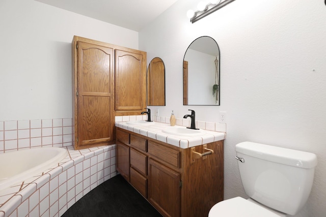 bathroom with vanity, toilet, and tiled tub