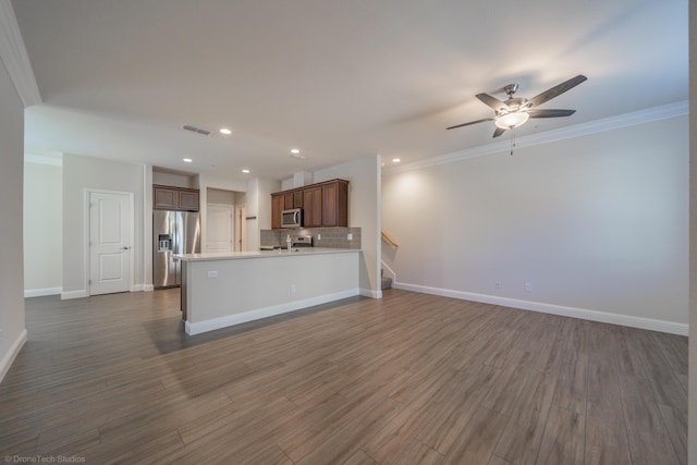 kitchen with ceiling fan, dark wood-type flooring, crown molding, decorative backsplash, and appliances with stainless steel finishes