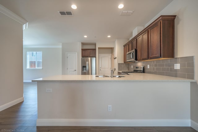 kitchen featuring kitchen peninsula, appliances with stainless steel finishes, crown molding, dark wood-type flooring, and sink