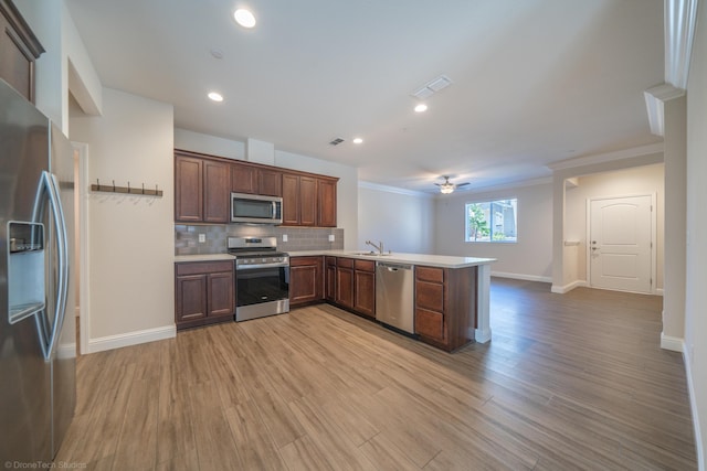 kitchen featuring kitchen peninsula, appliances with stainless steel finishes, light hardwood / wood-style floors, and decorative backsplash