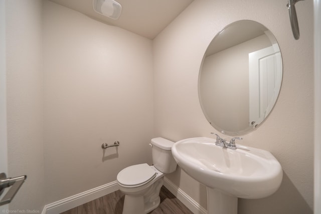 bathroom with toilet, wood-type flooring, and sink