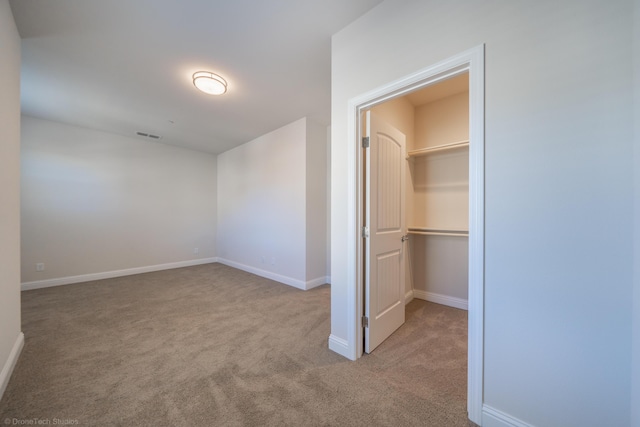 unfurnished bedroom featuring a walk in closet, light carpet, and a closet