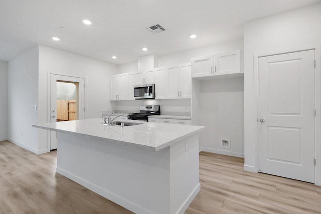 kitchen featuring sink, stainless steel appliances, light stone counters, a kitchen island with sink, and white cabinets