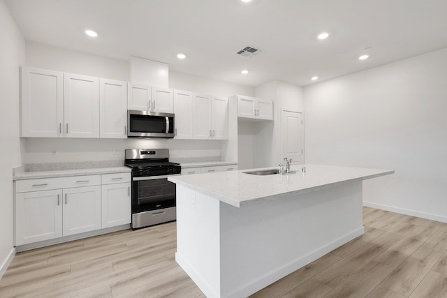 kitchen featuring appliances with stainless steel finishes, sink, a center island with sink, white cabinets, and light hardwood / wood-style floors