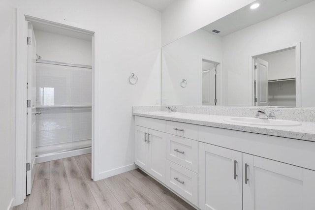 bathroom featuring vanity, a shower with shower door, and wood-type flooring