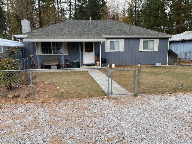 37412 Birch Ave, Burney, CA 96013 - view of front of house featuring a fenced front yard, a gate, a porch, board and batten siding, and a shingled roof